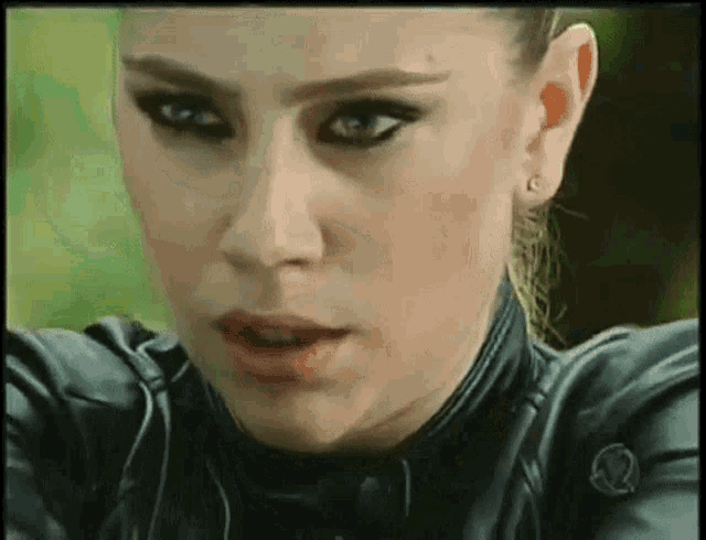 a close up of a woman 's face with a leather jacket on