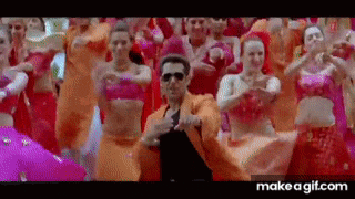 a man in an orange suit is dancing in front of a group of women in pink dresses .