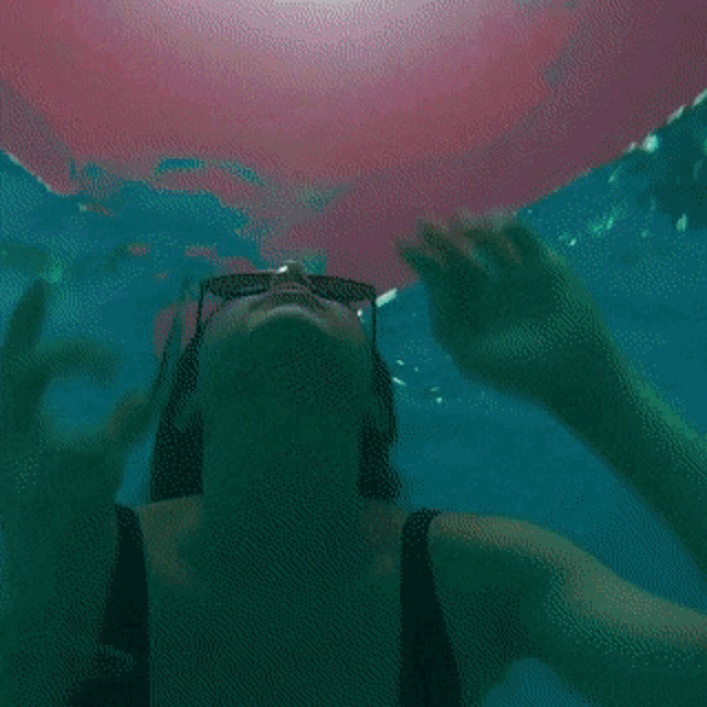 a woman wearing sunglasses is swimming underwater
