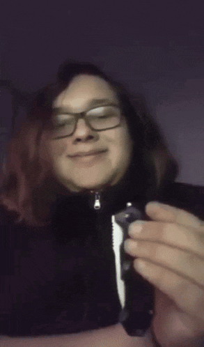 a woman wearing glasses is smiling and holding a piece of paper