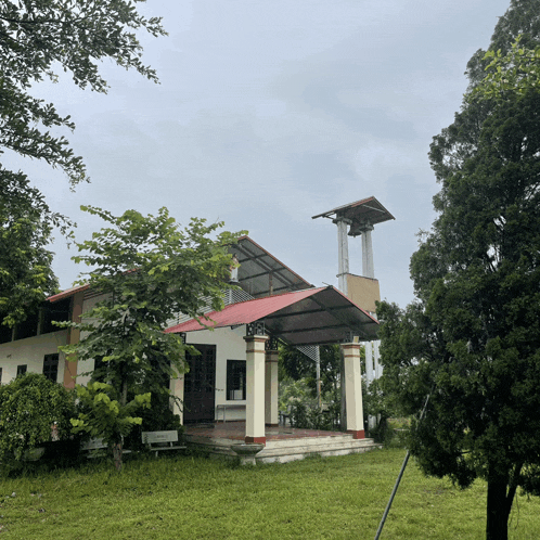 a church with a red roof and a bell tower is surrounded by trees