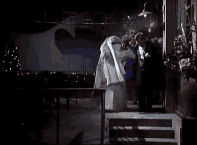 a bride and groom are standing in front of a crowd of people with the word crack on the wall behind them
