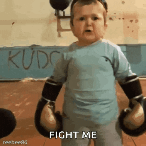 a baby wearing boxing gloves says fight me in a gym