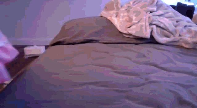 a bed with a blanket on top of it in a bedroom