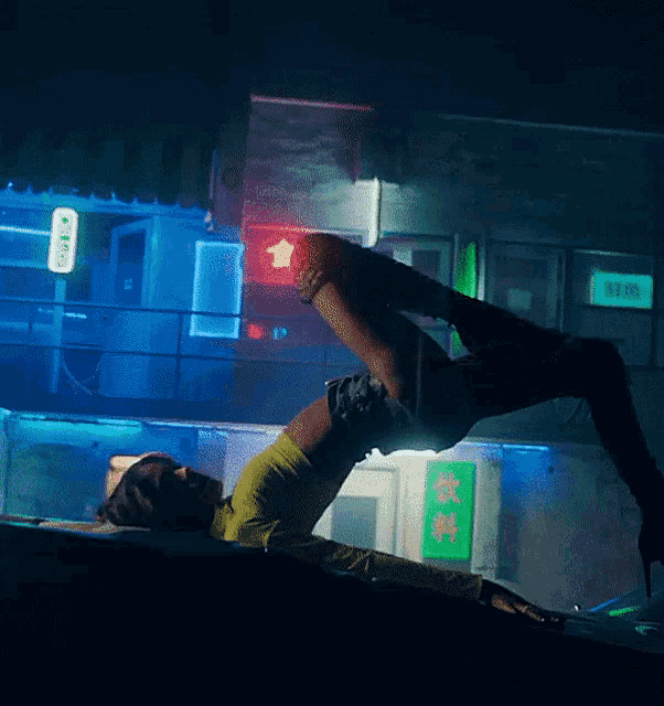 a woman is laying on her back in front of a building with a sign that says ' a ' on it