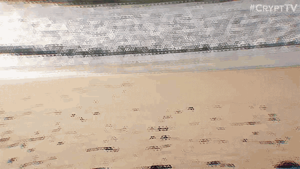 a person is walking on a beach with waves crashing against the shore .