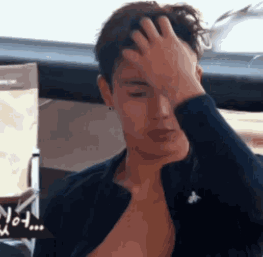 a man is scratching his head with his hand while wearing a black shirt .