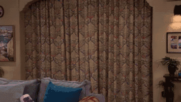 a woman is standing in a living room with her arms outstretched and a couch .