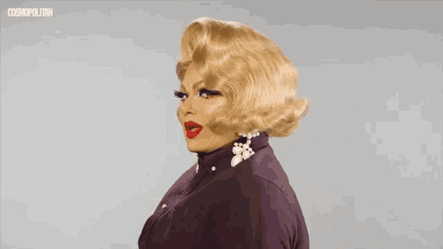 a drag queen is wearing a purple jacket with pearls on it