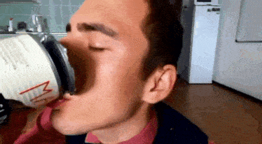 a man is drinking from a can with his eyes closed and his mouth open .