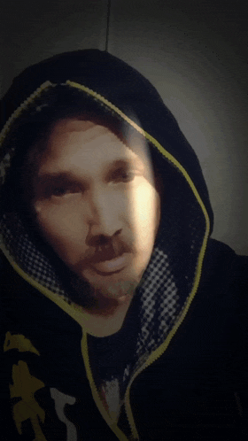 a man wearing a black and yellow hoodie with the letter x on the front