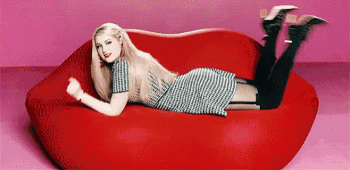 a woman is laying on a red couch that looks like a heart