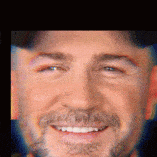 a man with a beard is smiling and wearing a baseball cap