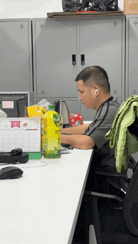 a man sitting at a desk with a bottle of fuze tea