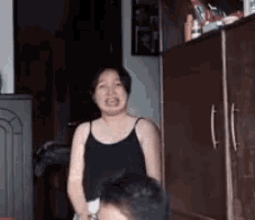 a woman in a black tank top is standing next to a man in a bedroom .