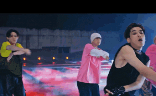 a group of young men are dancing on a stage in a video .