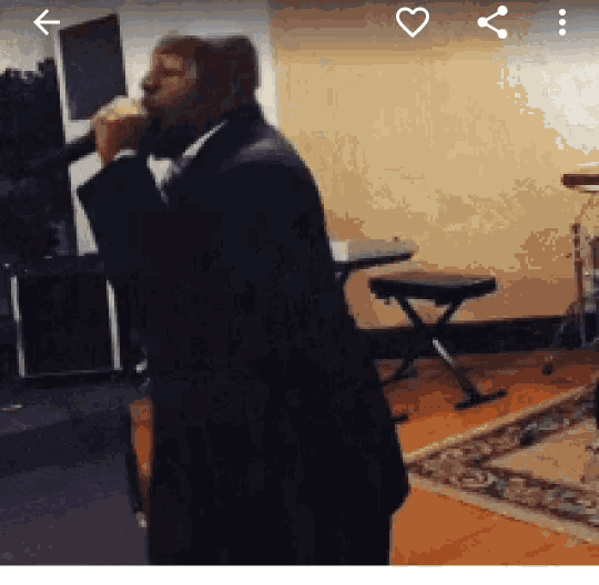 a man in a suit is singing into a microphone in a room