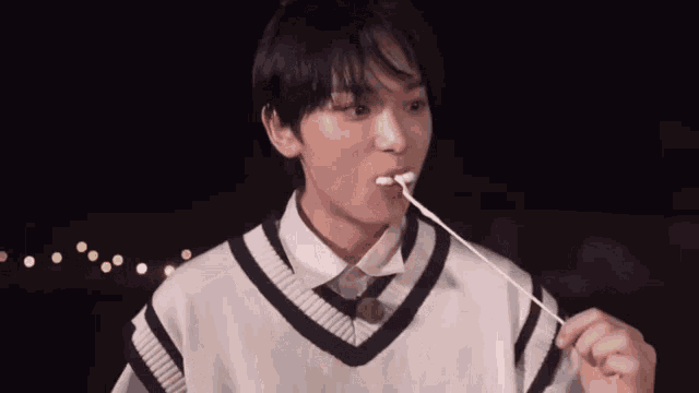 a young boy is eating a marshmallow on a stick .