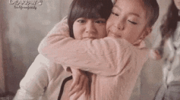 two girls are hugging each other and one of them is wearing a pink shirt .