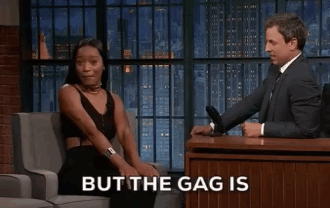 a woman is sitting in a chair talking to a man in a suit and the words but the gag is on the screen .