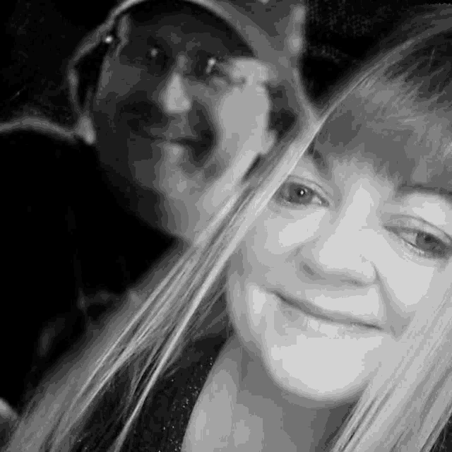 a black and white photo of a man and a woman smiling for a selfie .