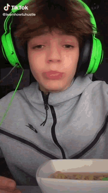 a boy wearing green headphones is eating a bowl of food