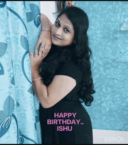 a woman in a black dress is standing in front of a blue curtain with the words happy birthday ishi written on it
