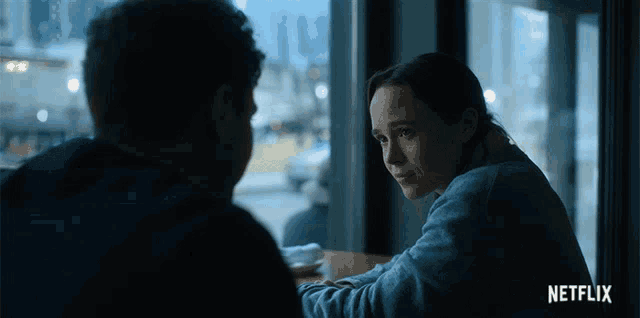 a man and a woman are sitting at a table with a netflix logo in the background