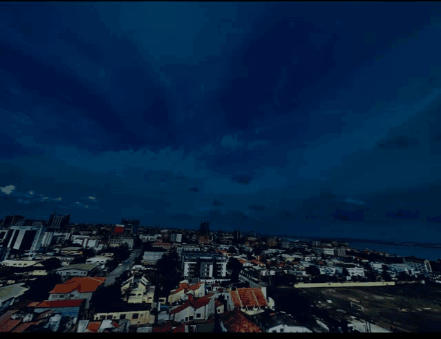 an aerial view of a city at night with a dark cloudy sky
