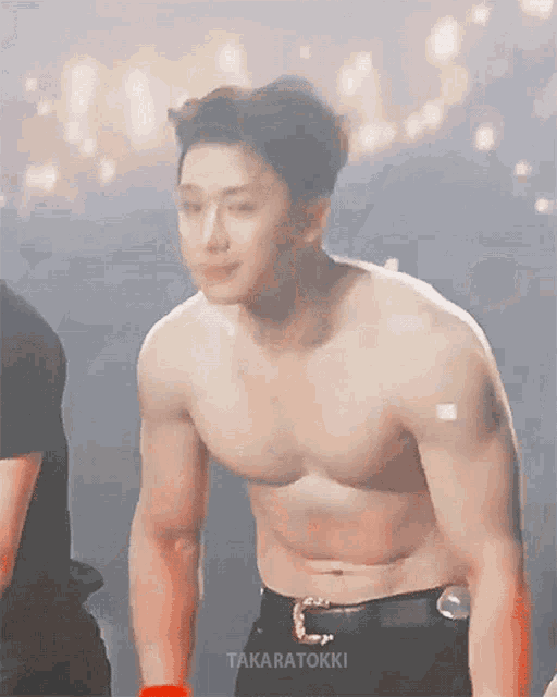 a shirtless man is standing in front of a crowd on a stage .