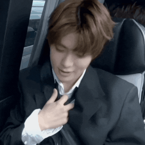 a man in a suit and tie is sitting in a car seat
