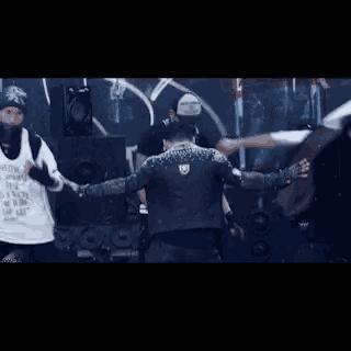 a group of people are dancing on a stage and one of them is wearing a black leather jacket with studs .