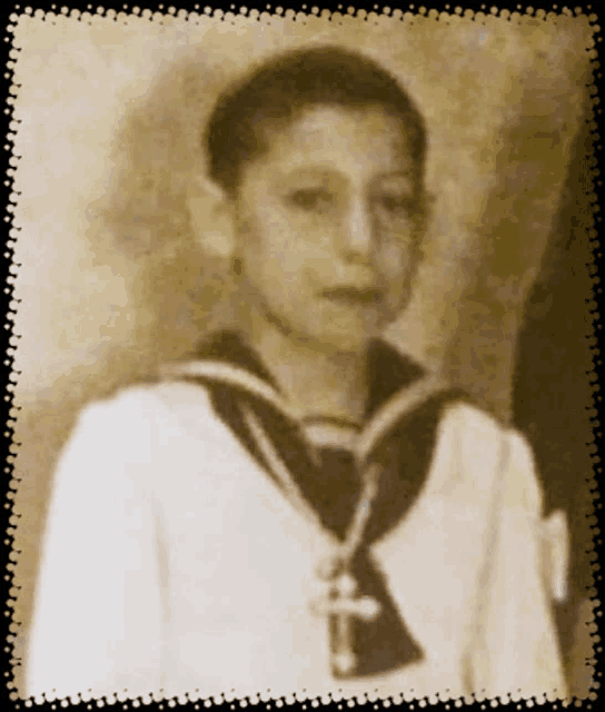 a black and white photo of a young boy wearing a sailor uniform
