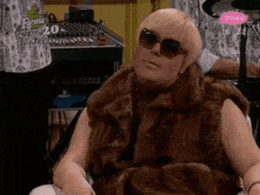 a woman wearing sunglasses and a fur vest is sitting in front of a drum set with the number 20 on it