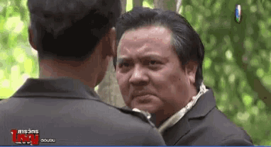 a man in a suit looks at another man in front of a screen that says ' lsoi ' on it