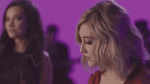 a woman is crying while sitting in front of a microphone in a purple room .