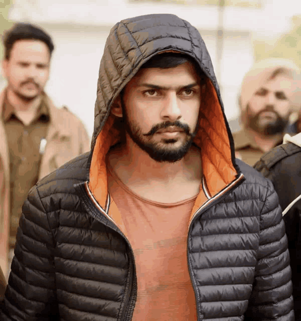 a man with a beard and mustache wearing a black jacket with a hood