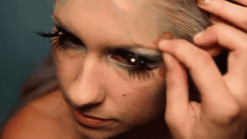 a woman with long eyelashes is applying makeup to her face