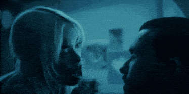 a man and a woman are looking at each other in the dark