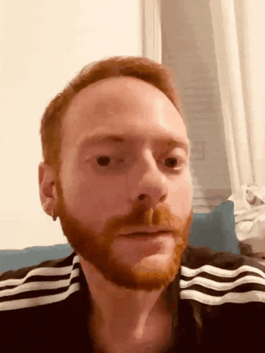 a man with red hair and a beard is wearing a black and white striped shirt
