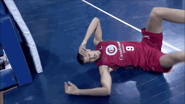 a basketball player laying on the floor wearing a casademar jersey