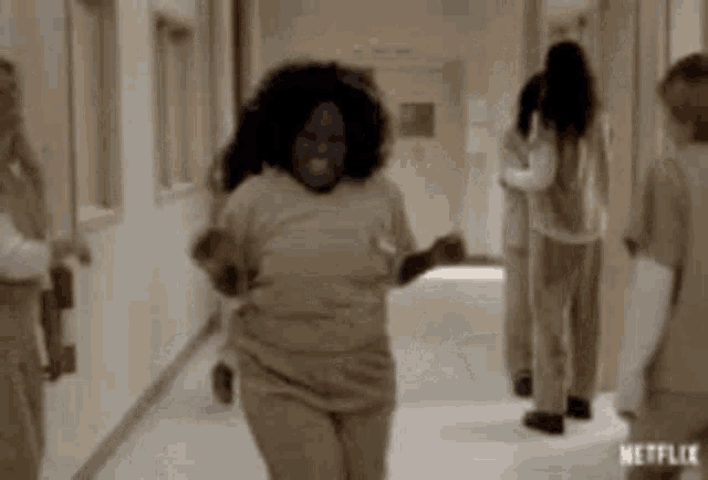 a woman is dancing in a hallway while a group of people are walking behind her .