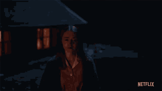 a woman is standing in front of a house at night with netflix written on the bottom