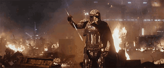 a storm trooper is holding a sword in front of a burning building