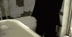 a person is standing in a bathtub with water pouring out of the faucet .