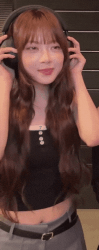 a woman with long hair wearing headphones and a black tank top