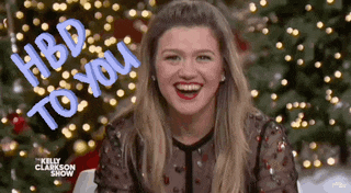 kelly clarkson is smiling in front of a christmas tree