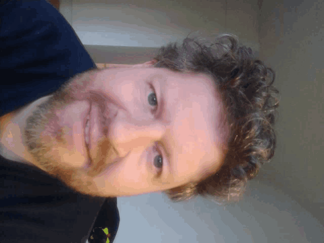 a man with a beard and curly hair is smiling for the camera