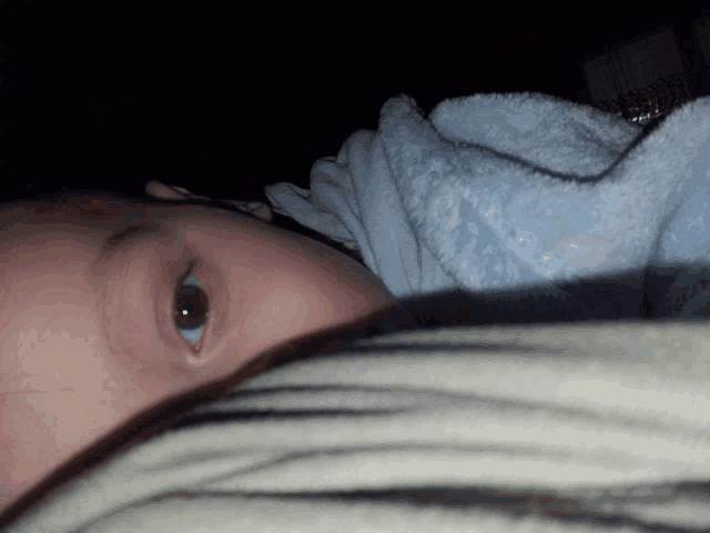 a close up of a baby 's face with a blue blanket