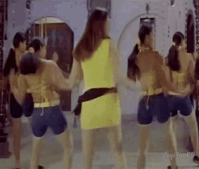 a group of women are dancing in front of a mirror .
